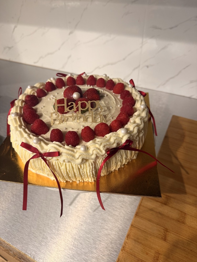 Sahnetorte mit frischen Himbeeren und roten Schleifen