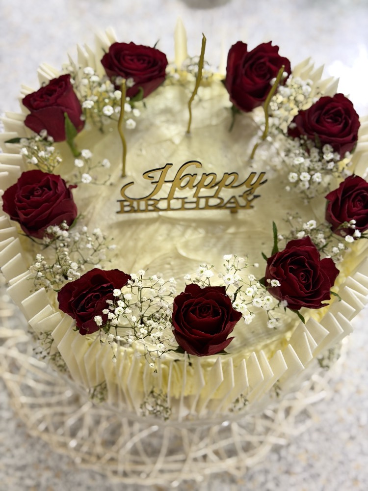 Weiße Sahnetorte mit roten Rosen und Happy-Birthday-Schriftzug